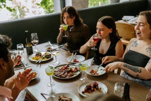 People seated at a restaurant table dining from shared dishes.