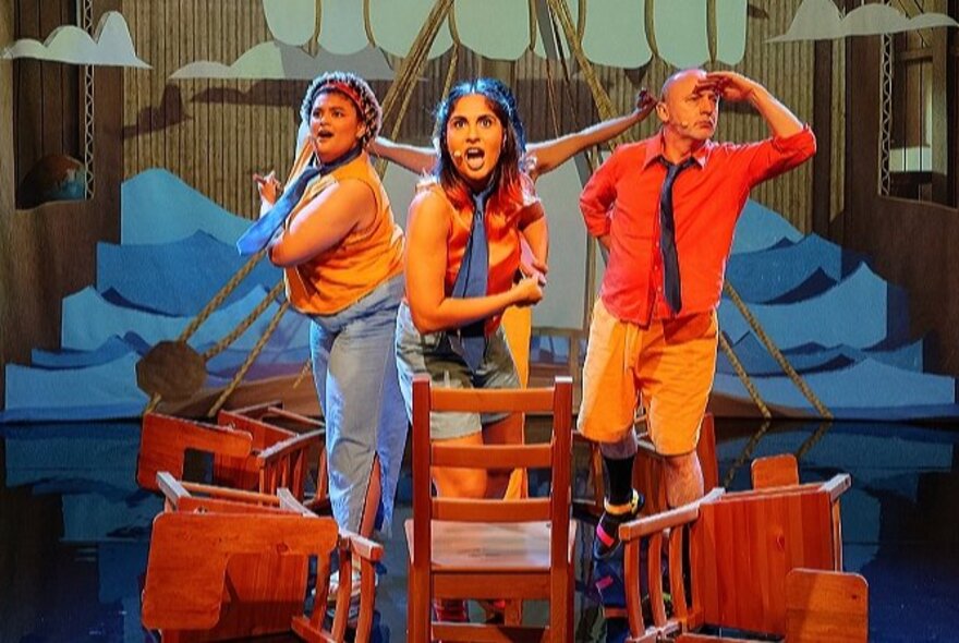 Three people marooned on stage, surrounded by chairs, looking lost.