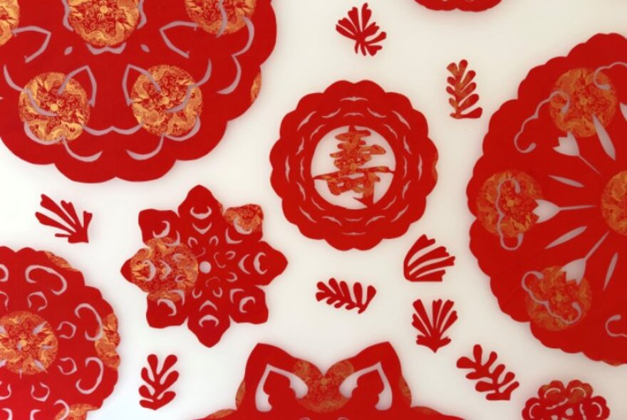 Red cut-paper motifs laid out on a cream coloured background.