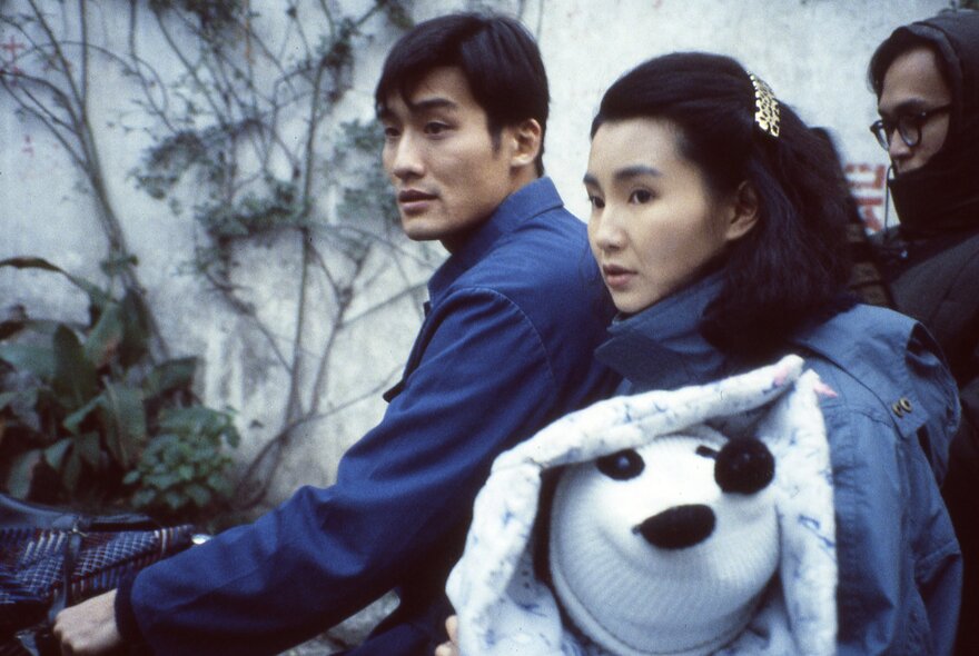 Film still of two Asian actors with winter trees in the background.