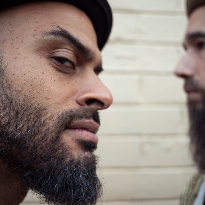 Two members of Cool Out Sun, one looking out of the corner of his eye menacingly. 