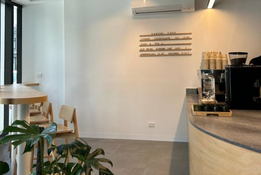 Corner cafe in a lobby, showing wooden servery area and a coffee machine.