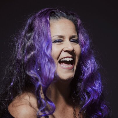 Jazz singer Michelle Nicolle with purple hair, laughing. 