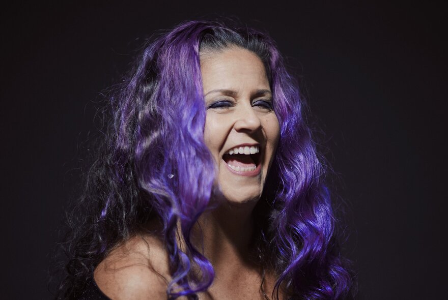 Jazz singer Michelle Nicolle with purple hair, laughing. 