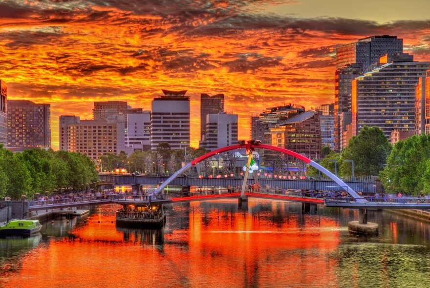 An image of the Melbourne skyline taken from the Yarra river, bathed in an orange sunset glow.