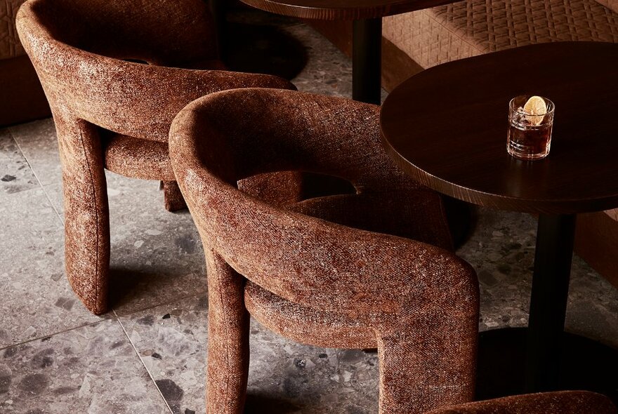 Unusual round seats at round tables with a drink, on a marble tiled floor.