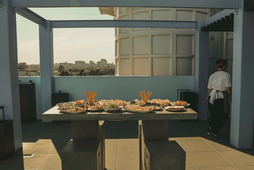Table set with pizzas in an outdoor rooftop setting.