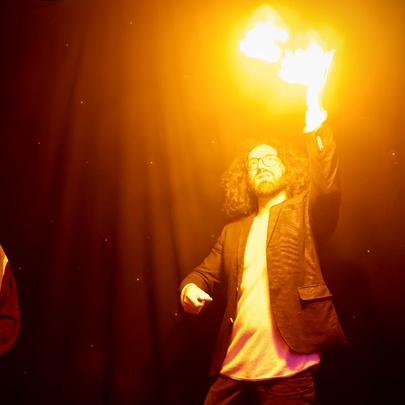 A magician performing a magic trick with fire while a man looks on. 