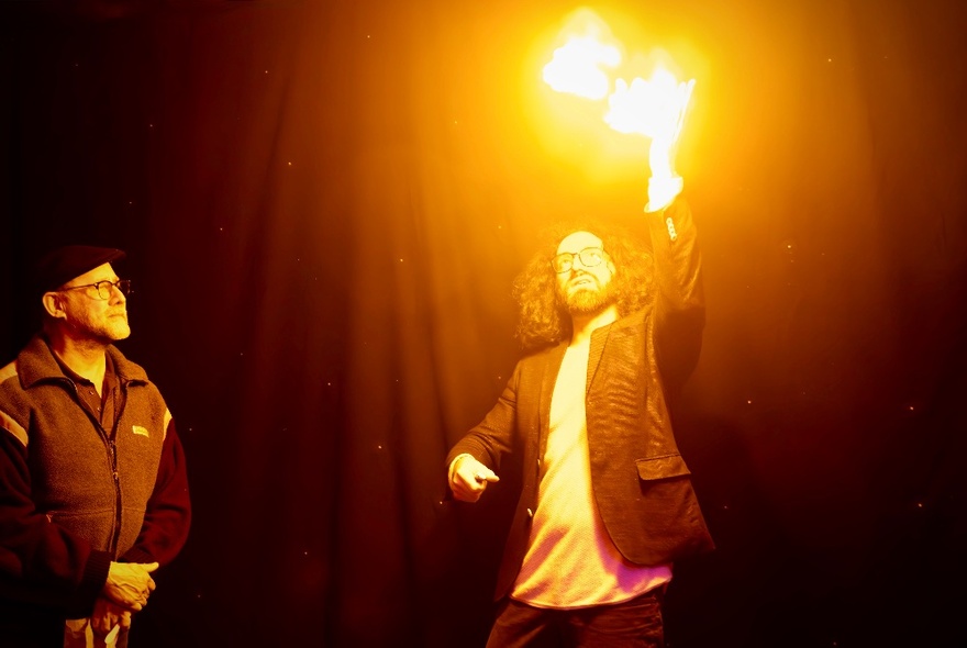A magician performing a magic trick with fire while a man looks on. 