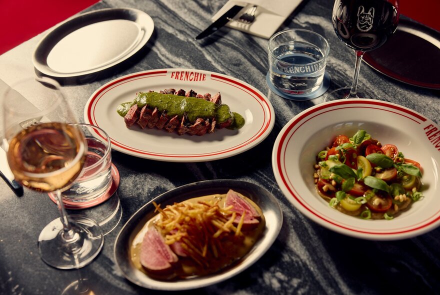 A table at a restaurant with plates of steak, salad and French fries