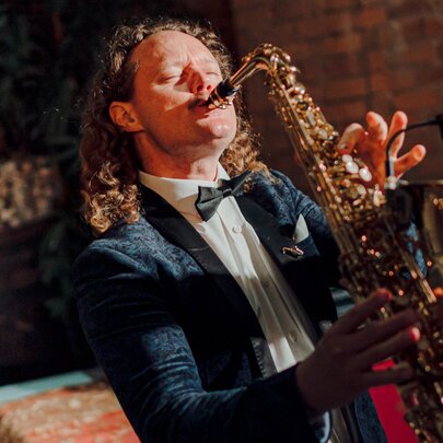A man wearing a suit playing saxophone in a bar.