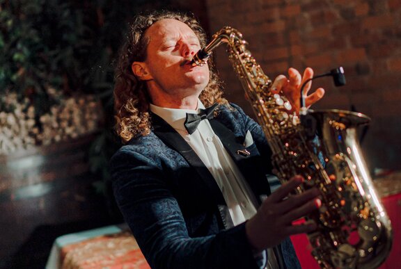 A man wearing a suit playing saxophone in a bar.