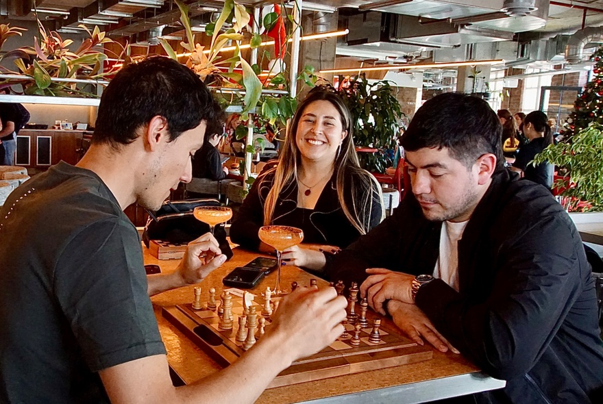 People playing chess at a table in a publike venue.
