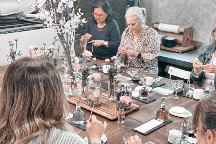 An elevated view of a candle-making workshop with women working at a large table.