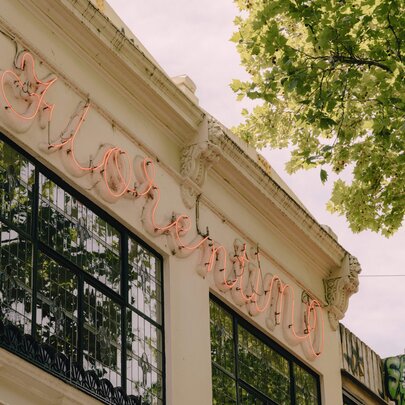 The historic exterior facade and iconic pink neon sign of Florentino against a very pale blue sky.