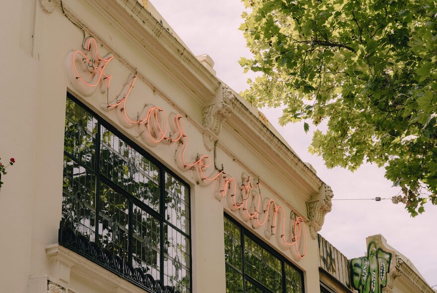 The historic exterior facade and iconic pink neon sign of Florentino against a very pale blue sky.