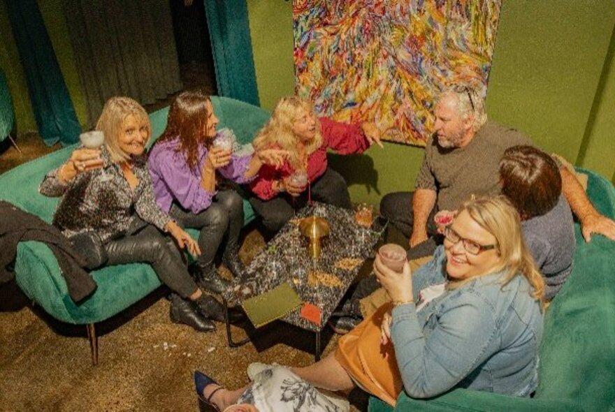 People seated on sofas at a bar enjoying drinks and socialising.