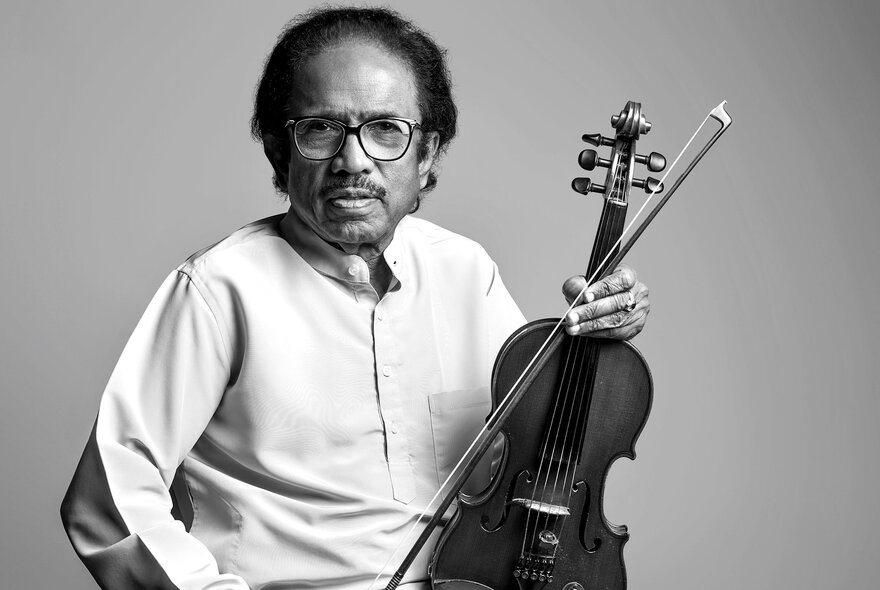 Black and white image of Dr. L. Subramaniam wearing a white shirt holding a violin.
