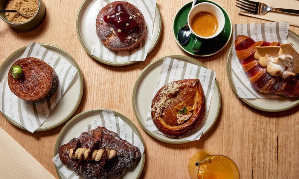 Topdown image of a wooden table covered in pastries and coffee.