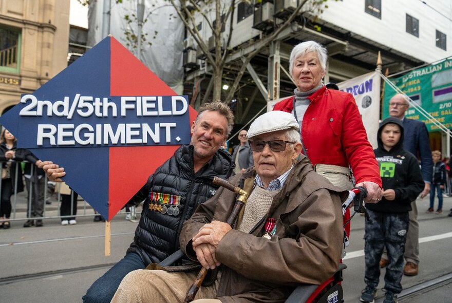 People participating in the ANZAC Day march through Melbourne, a man being pushed in a wheelchair. 