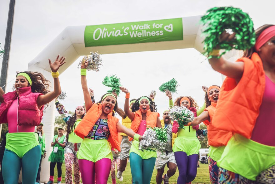 Walkers entering the finish line of a charity walk, wearing brightly coloured running shorts and leggings.