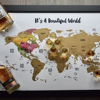 A framed world map titled 'It's A Beautiful World' surrounded by several bottles of whiskey and small tasting glasses.