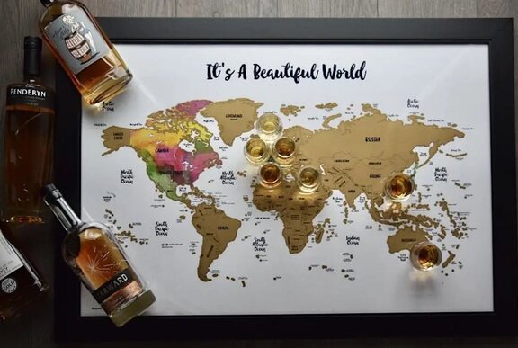 A framed world map titled 'It's A Beautiful World' surrounded by several bottles of whiskey and small tasting glasses.