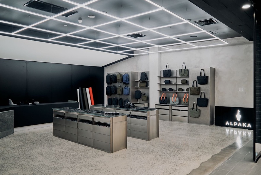 The minimalist grey interiors of the Docklands Alpaka store with concrete floors and a shelf of bags at the rear.