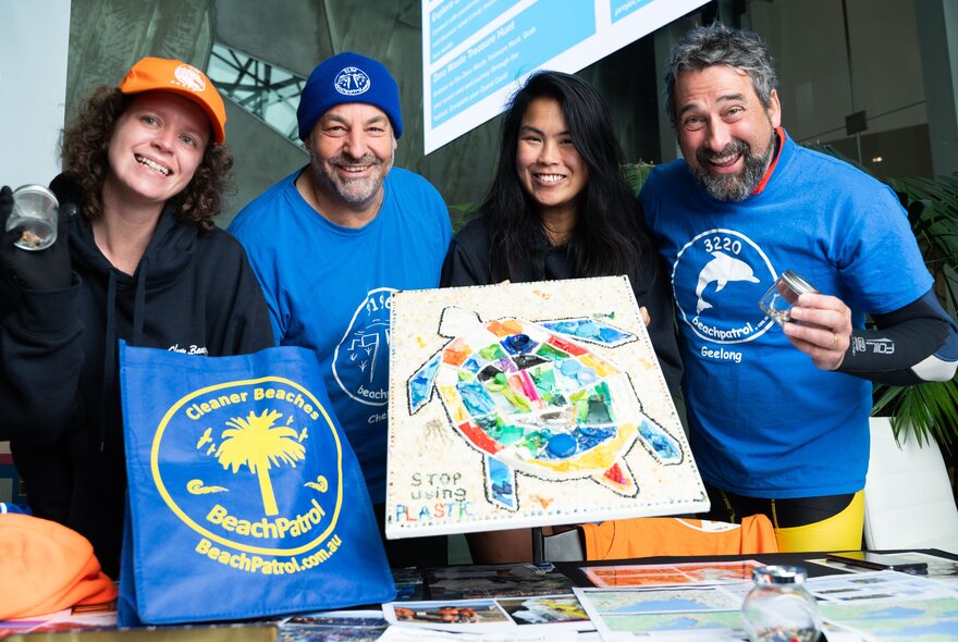 Presenters wearing logo T-shirts holding turtle artworks.