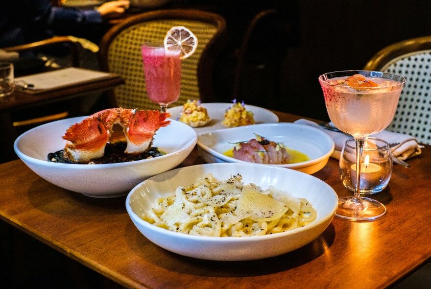 A restaurant table set with pasta dishes and cocktails. 