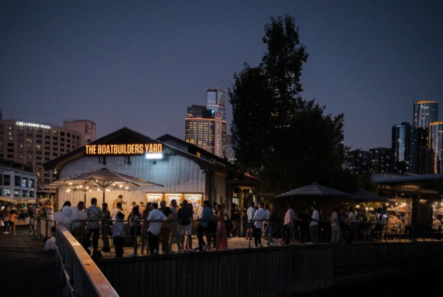 The Boatbuilder's Yard venue at night, with people standing out the front, silhouettes of trees.