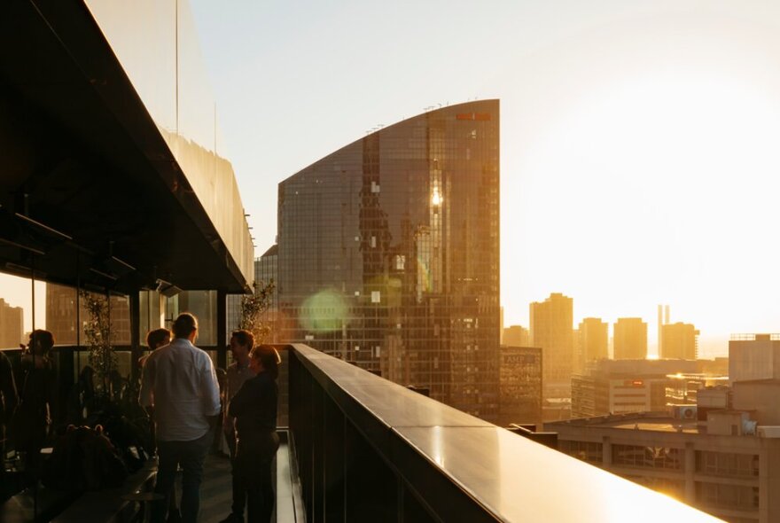 A rooftop bar at sunset, with patrons enjoying the atmosphere.