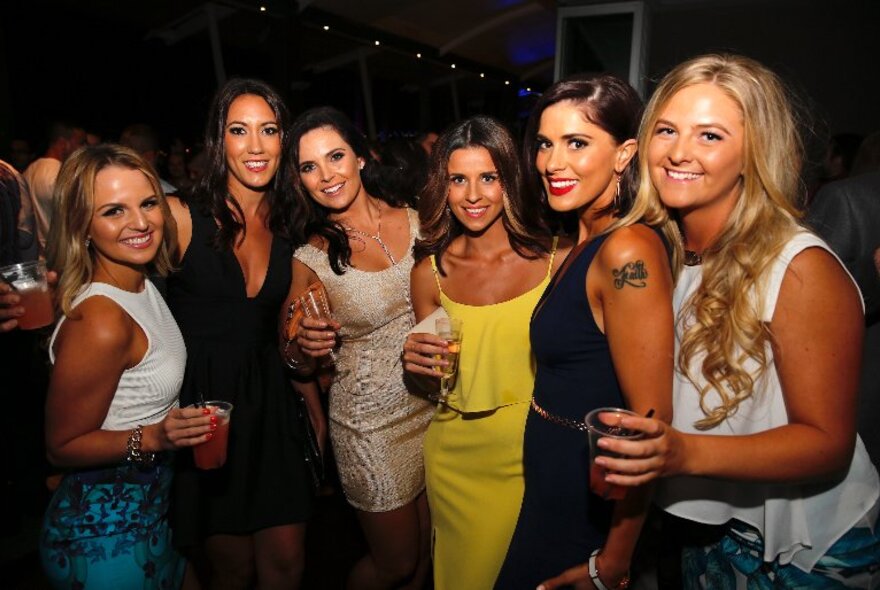 A group of attractive women posing for a photo at a nightclub.