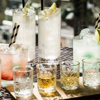 A selection of cocktails in different sized glasses arranged on a table.