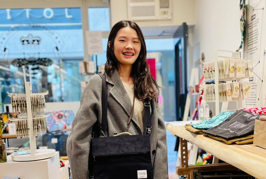 Smiling customer inside a retail space with products on display on a counter and on small display racks.