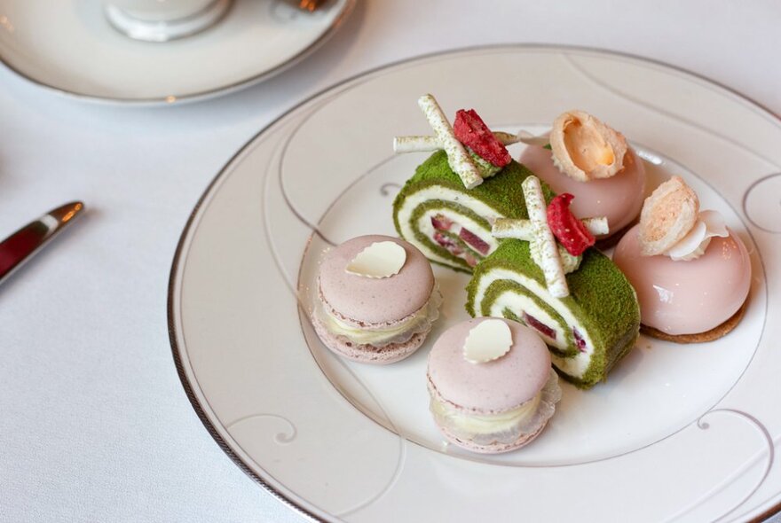 A fine china plate with a selection of delicate sweet and savoury afternoon tea food on it.