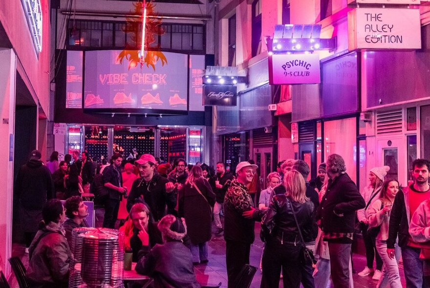 People milling in Capitol Arcade in Howey Place under purple lights.