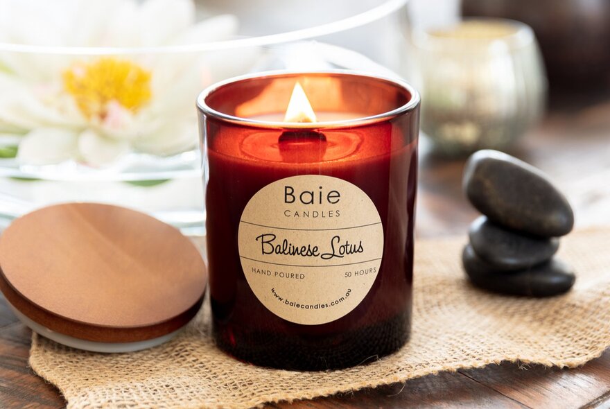 A lit scented candle on a table at a market stall.