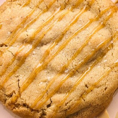 Close up of caramel macadamia nut cookie, drizzled with syrup.