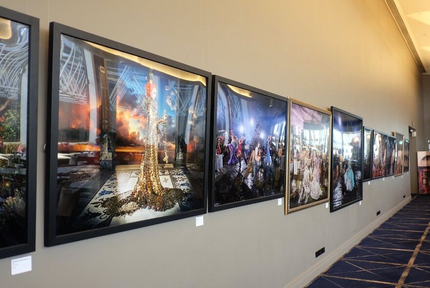 A white wall in a room lined with large scale framed photographic works.