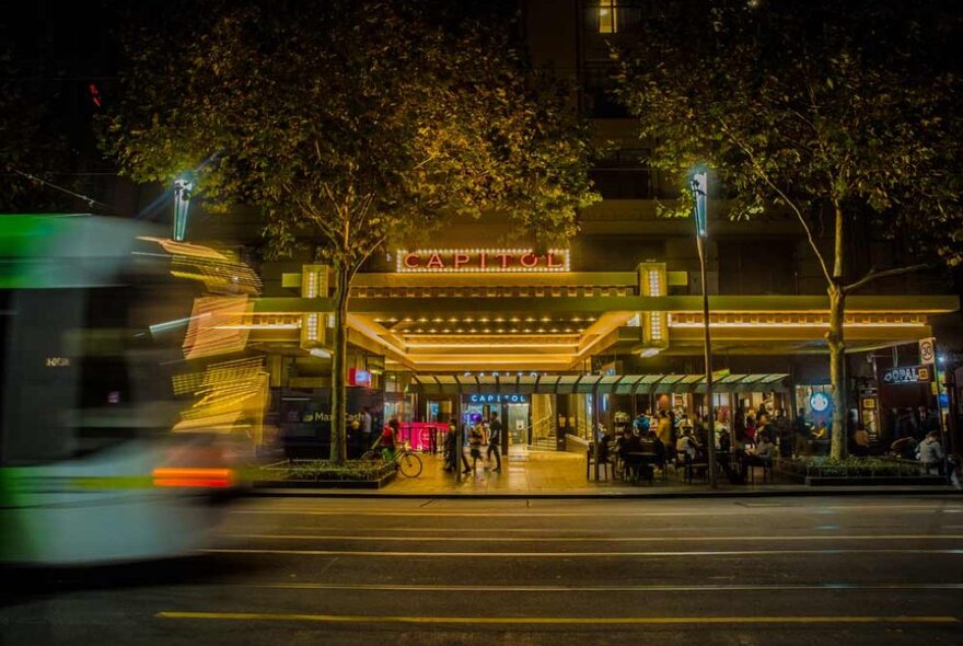 A tram going past a theatre in the evening