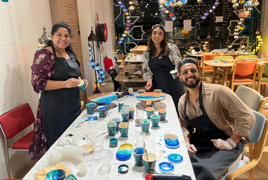 People working at a crafts table with pots of resin.