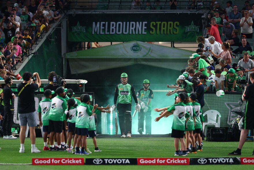Players emerge from the rooms at a BBL match to a line of kids waiting to greet them on the ground. 