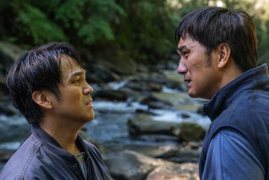 A still image from a Taiwanese film of two men arguing at a stream, both distressed.