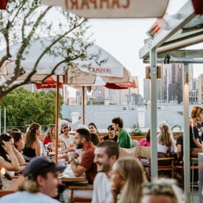 People drinking and dining in an outdoor rooftop courtyard.