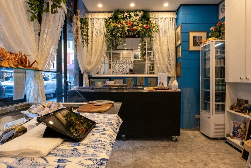 The interior of a seafood bar with blue walls and lace curtains.