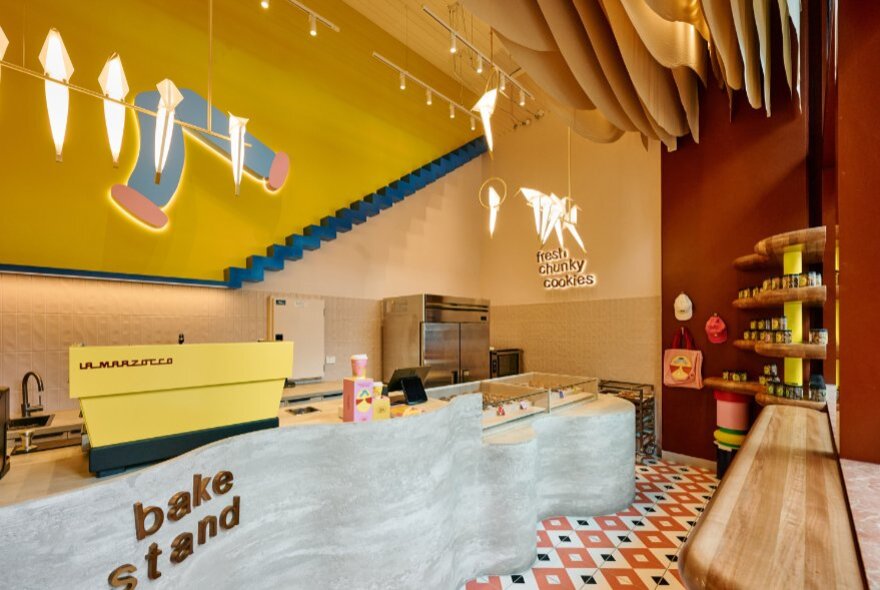 The interior of a cookie store in Melbourne, featuring yellow walls, a curved counter and a wooden bench.