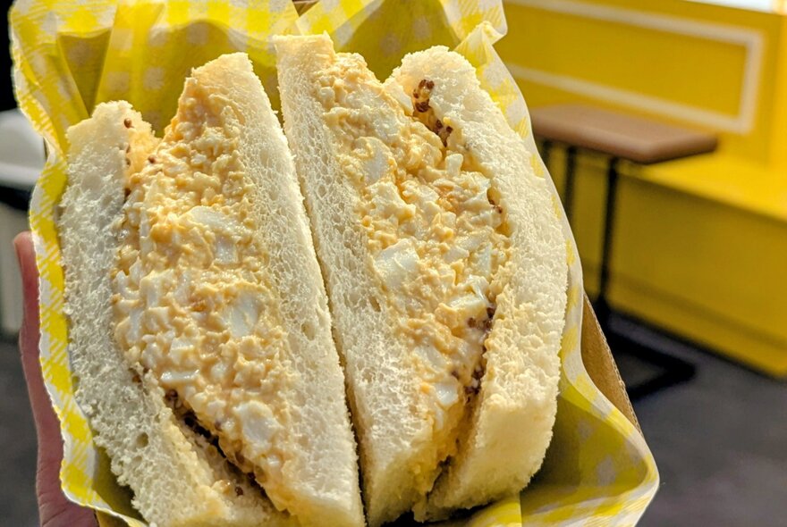 An egg sandwich in a cardboard tray with yellow paper lining.
