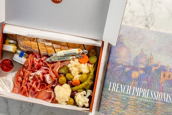 A charcuterie box next to a book on French Impressionism