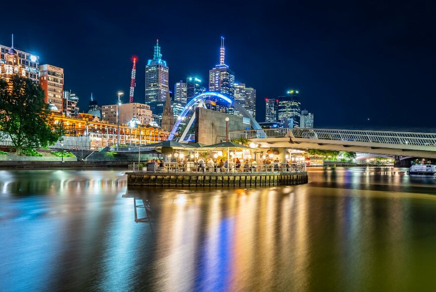 A floating bar on a river at night with the city skyline in the background